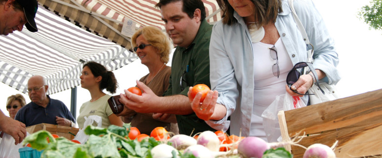 Customers examine tomatoes at the Riverfront FarmersÕ Market. FILE PHOTO